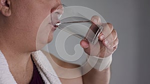 Close-up of chubby man drinking fresh water from glass, healthy weight loss diet