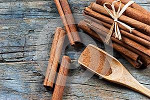 Close up cinnamon sticks and cinnamon powder in wooden spoon on wooden table background