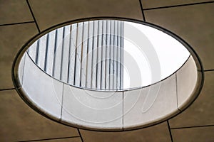 Close up of circular skylight with view of the concrete building exterior wall