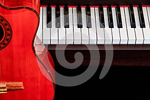 Close up of classic guitar over grand piano keys for music background with copy space