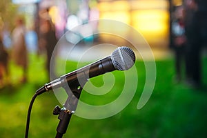Close up classic microphone on Abstract blurred bright green background of conference hall or event. Public speaking concept.