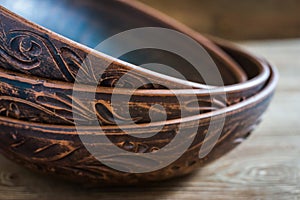 Close up of clay plates with handmade red clay patterns on top of each other on a wooden table