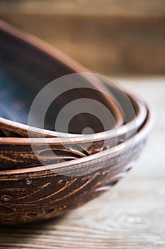 Close up of clay plates with handmade red clay patterns on top of each other on a wooden table