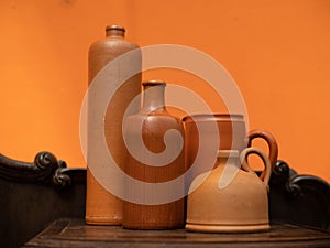 Close-up of clay vessels. Bottles and jugs. Orange wall on background.