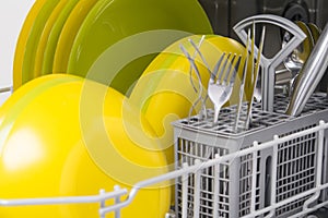 Close-up of clean metal cutlery and plates, in the dishwasher, after work