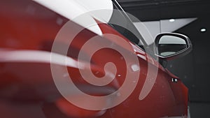 Close up of clean, shiny, new car stands in the parking lot of the shopping center. Action. Beautiful luxury red car