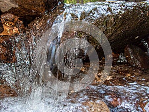 Close up of clean water flowing over a stone in an idyllic woodland stream