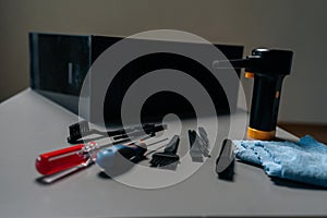 Close-up of cleaning open computer case with specialized tools, screwdrivers and brushes on gray table in workshop