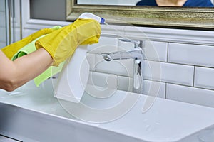 Close-up of cleaning sink with faucet in bathroom, hands in gloves with detergent photo