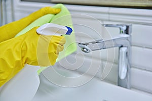 Close-up of cleaning sink with faucet in bathroom, hands in gloves with detergent photo