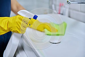 Close-up of cleaning sink with faucet in bathroom, hands in gloves with detergent photo