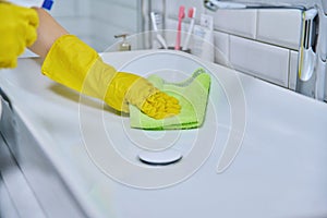 Close-up of cleaning sink with faucet in bathroom, hands in gloves with detergent photo