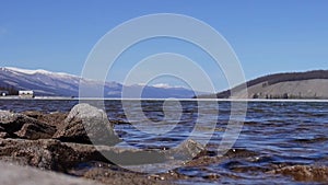 Close-up of clear clear water of Lake Khuvsgul in Mongolia. In the background snow-capped mountains