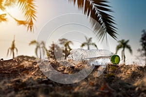 Close up clear plastic bottle water drink with a green cap on the road in the park at blurred background, Trash that is left