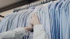 Close-up of the client's hands. Unrecognizable man, chooses a shirt in a clothing store.