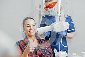 Close up of client smiling and showing thumb up while dentist holding x-ray