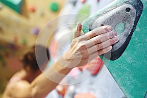 Close-up climber hand in chalk powder gripping hold.