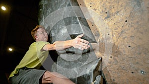 CLOSE UP: Climber reaches up to grip a hold while training at indoor center.