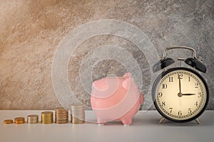 Close-up of clock and pink piggy bank with coins stack stair step up growing growth saving money. concept Business Finance