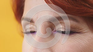 Close up of closed eyes with purple and gold eyeshadow of mature red hair woman