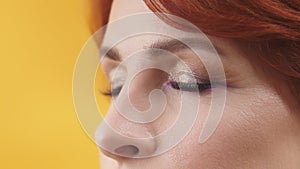 Close up of closed eyes with purple and gold eyeshadow of mature red hair woman