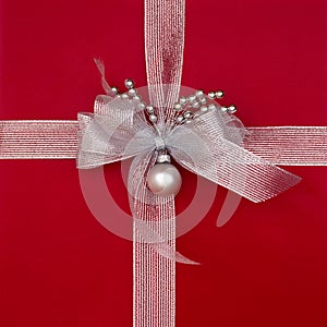 Close-up closeup of red Christmas gift present with metalllic silver ribbon, bow and decorations. Beautiful, fancy, elegant