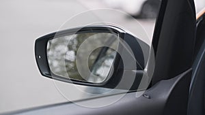 Close up of closing the car window. Action. View from the car interior to the side window and and a mirror on street