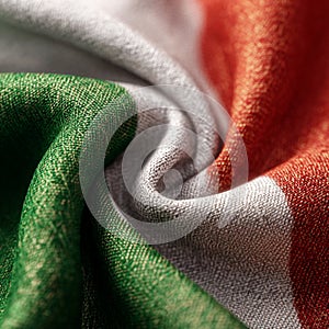 Close up of a cloth with green white and orange stripes creating a wavy pattern on the fabric surface