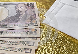 Close-up on cloth masks and 100,000 yen in cash on a golden paper.