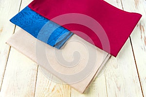 Close up of cloth napkins of beige, blue and burgundy colors on rustic white wooden table. Shallow depth of field