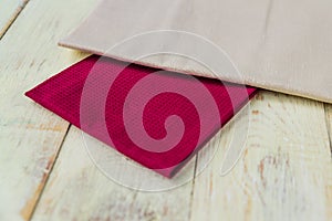 Close up of cloth napkins of beige and burgundy colors on rustic white wooden table. Shallow depth of field