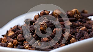 Close up cloves spice. Some dried cloves in a white bowl.