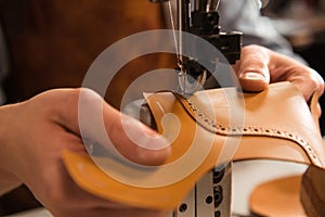 Close up of a cobbler stitching a part of shoe photo