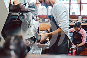 Close-up of cobbler working on pair of shoes with machine