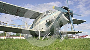 Close-up of cockpit fuselage of old USSR airplane standing in thick grass of overgrown field against sunset in slow