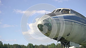 Close-up of cockpit fuselage of old USSR airplane standing in thick grass of overgrown field against sunset in slow