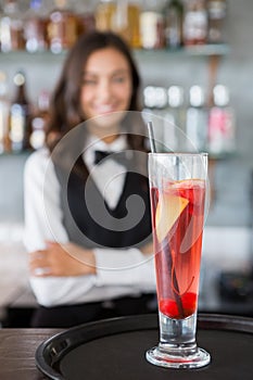 Close-up of cocktail glass in tray with waitress in background