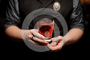 Close-up of cocktail with orange rind in bartender`s hands
