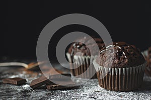 Close up of cocoa muffins with chocolate icing on rustic table c