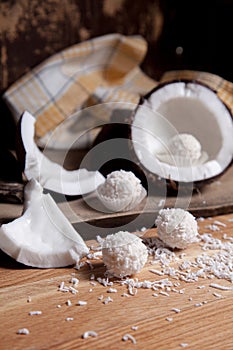 Close up of coconut with white pulp, coconut chip and white candies on wooden background