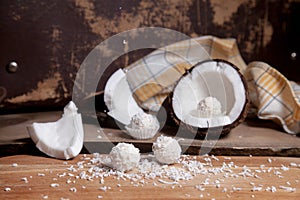 Close up of coconut with white pulp, coconut chip and white candies on wooden background