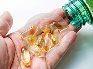 A close-up of cod liver oil capsules in the palm of a hand.