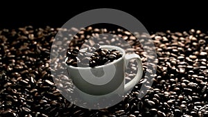 Close up of coffee bean falling in to coffee cup surrounded by bean. Comestible. photo