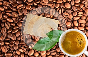 Close-up of coffee cup, beans background, leaves and blank tag