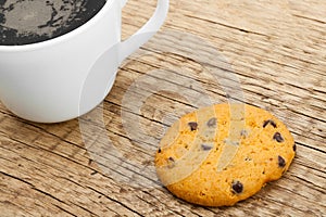 Close up of coffee cup and a cookie on old rustic wooden table