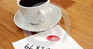 Close-up of coffee cup with lipstick mark and message written on tissue