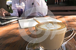 Close up coffee latte art and background business woman working outdoor in coffee shop vintage tone