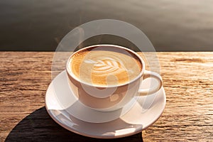 Close up a coffee latte in white cup and milk froth above to drink on brown wooden table background, increase energy for today