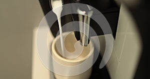 Close up of a coffee maker making coffee in a white cup. I pour the coffee stream from a