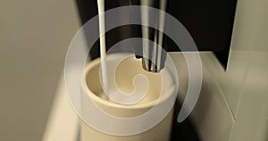 Close up of a coffee maker making coffee in a white cup. I pour the coffee stream from a